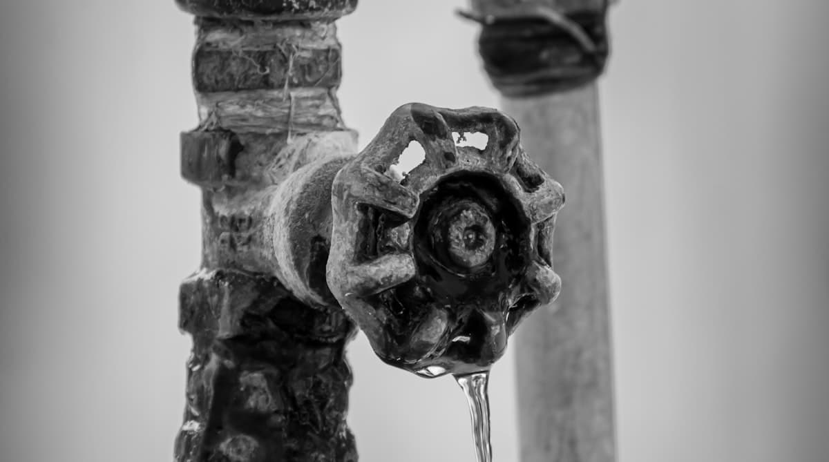 Homeowner turning off main water shut-off valve during a plumbing emergency