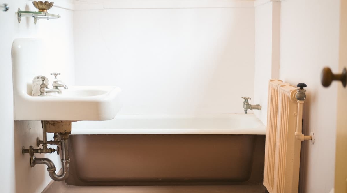 Applying a smooth bead of white silicone caulk along a bathtub edge