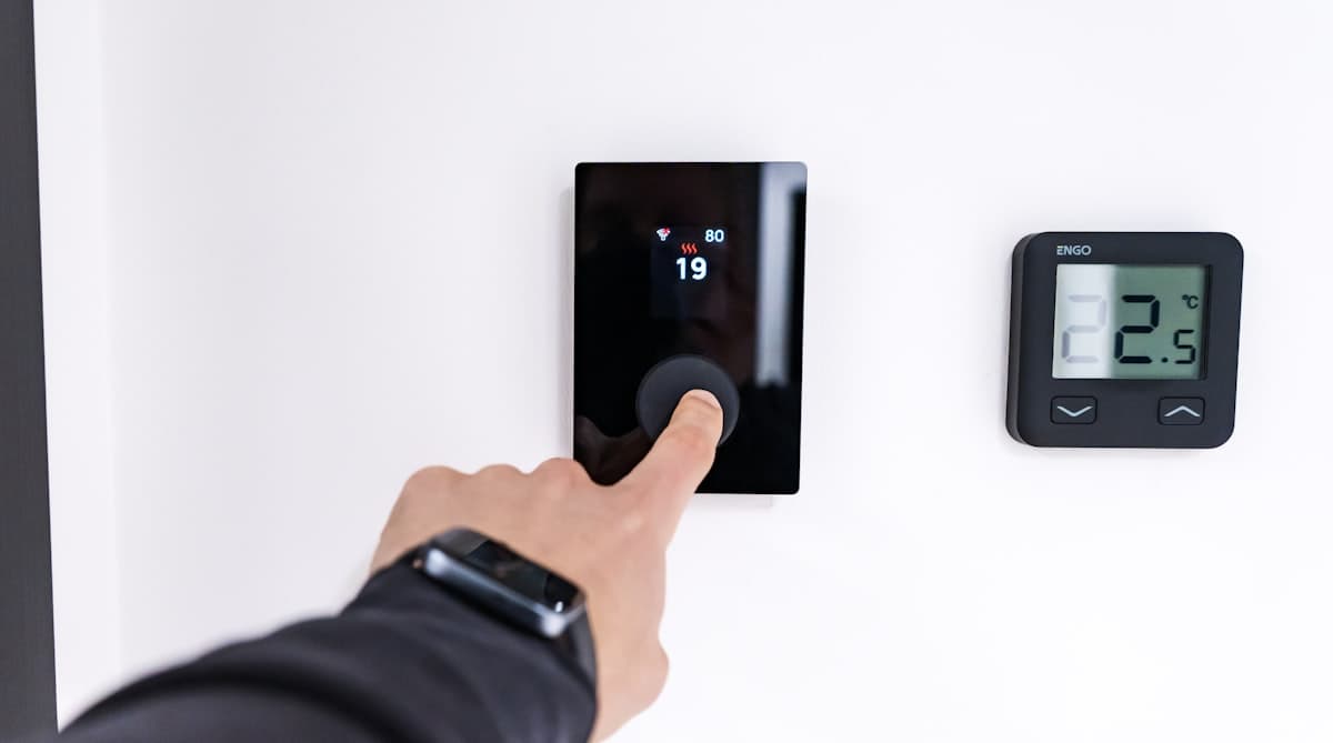 Smart thermostat mounted on living room wall showing temperature display
