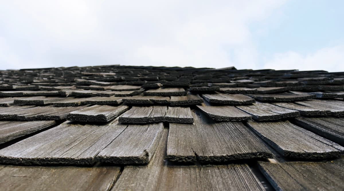 Close-up of aged wood roof shingles showing curling, splitting, and weather damage